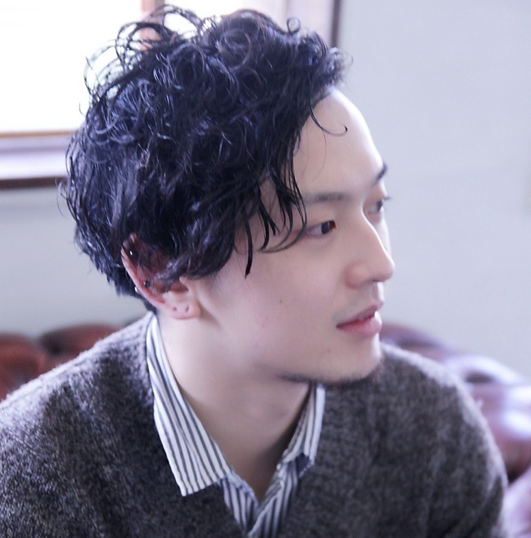 右を向くパーマをかけた男性の写真