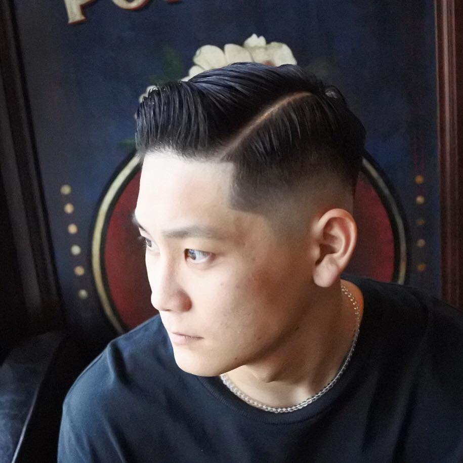 左を向く前髪を立ち上げたフェードスタイルの男性の写真