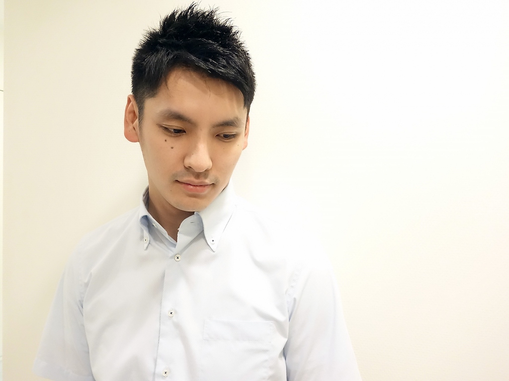 下を向くビジネスショートの男性の写真