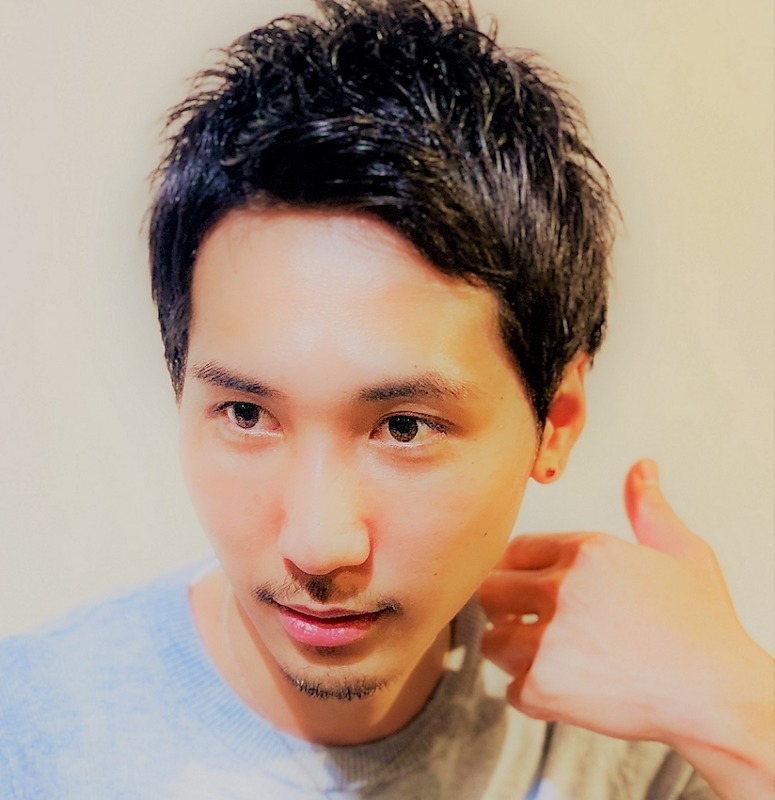 首に手をあてるショートヘアの男性の写真