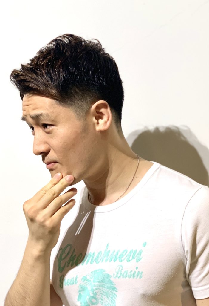 あごに手を当てる刈り上げスタイルの男性の写真